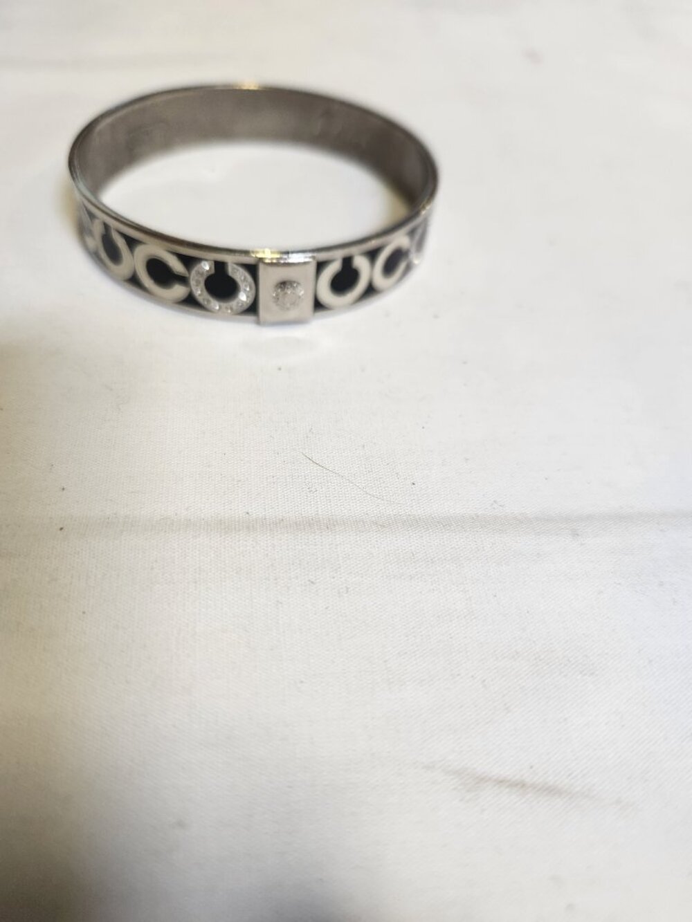 This Coach silver-tone stainless steel bangle bracelet features a cut-out signat